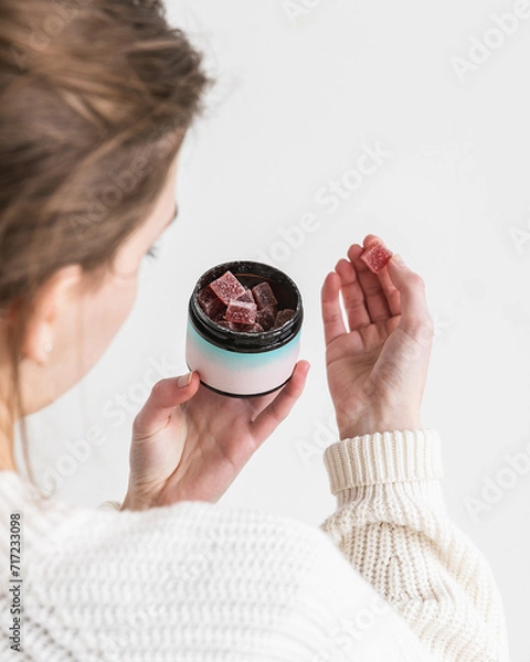 Fototapeta Woman holding CBD gummy in hand to take
