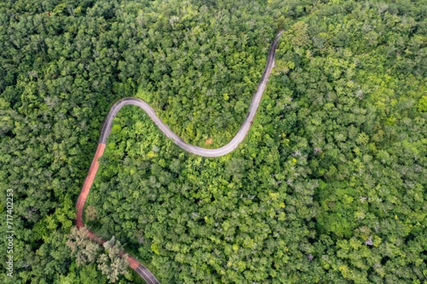 Fototapeta Top view of countryside road passing through the green forrest and mountain