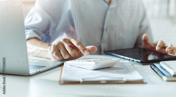 Fototapeta Close-up shot, businessmen or accountant using calculator calculate expenses and budget to planning and start new business and use a tablet to check orders from customers