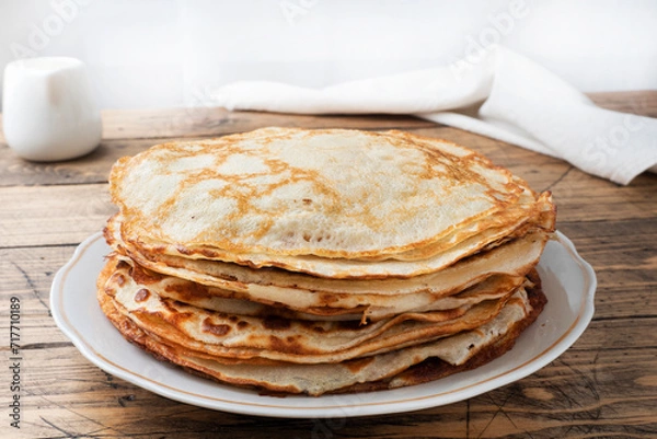 Fototapeta Thin pancakes on a plate, wooden background. The concept of a delicious breakfast or Maslenitsa