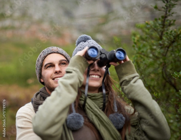 Fototapeta Couple, love and binocular in nature for travel, adventure or hiking journey and explore together in eco friendly mountains. Happy man and woman trekking with outdoor search, vision or birdwatching