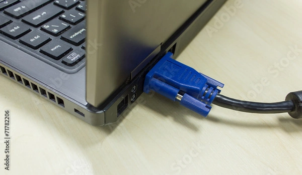 Obraz VGA cable connected to laptop on wooden table