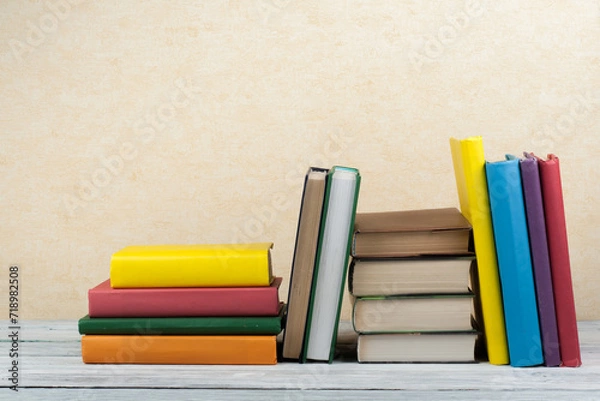 Obraz Book stacking. Open book, hardback books on wooden table and blue background. Back to school. Copy space for text.
