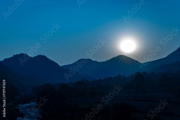 Fototapeta full moonrise dramatic landscape with mountain range at night from flat angle