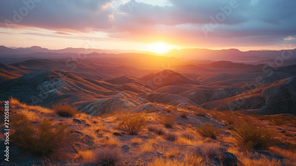 Obraz Desert Landscape at Golden Hour with Mountain Range - The sun sets behind a mountain range, casting a golden glow over the desert landscape and highlighting the textured grasses.