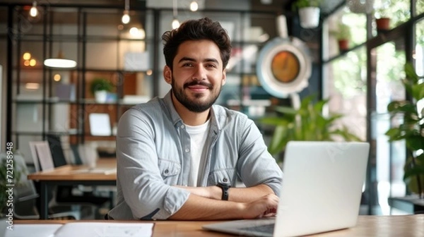 Fototapeta Modern Office: Portrait of Stylish Hispanic Businessman Works on Laptop, Does Data Analysis and Creative Designer