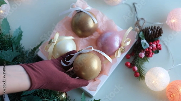 Fototapeta Female hand in glove stacking chocolate balls of different colors in a gift box. Chocolate balls in a box