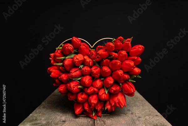 Fototapeta red tulips tied as heart shape on table with black background and space for text