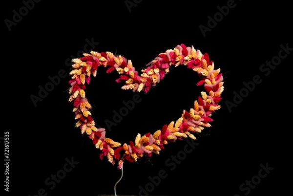 Fototapeta dried flowers tied as heart shape on black background with space for text