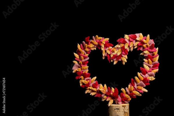 Fototapeta dried flowers tied as heart shape on black background with space for text
