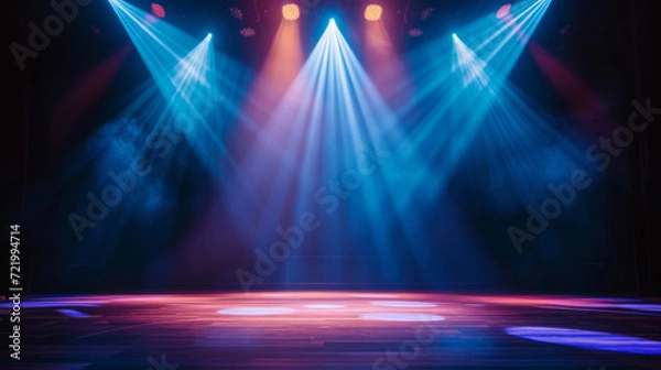Fototapeta An empty stage is dramatically lit with vibrant blue and purple spotlights, casting a hazy glow and creating an anticipation for the upcoming performance