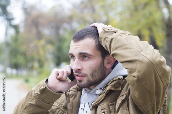 Obraz Young  worried man talking on phone
