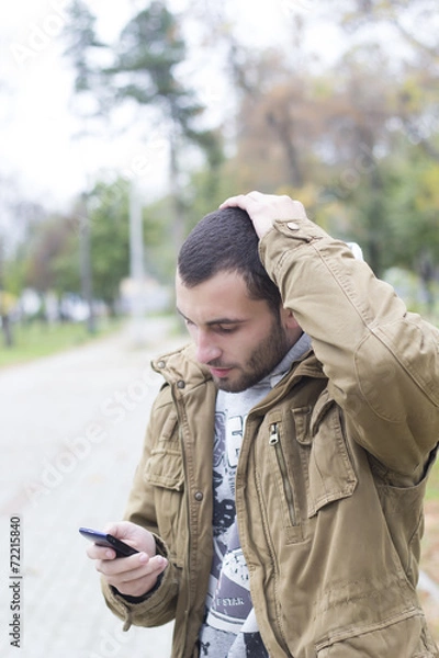 Obraz MAn upset looking at his phone