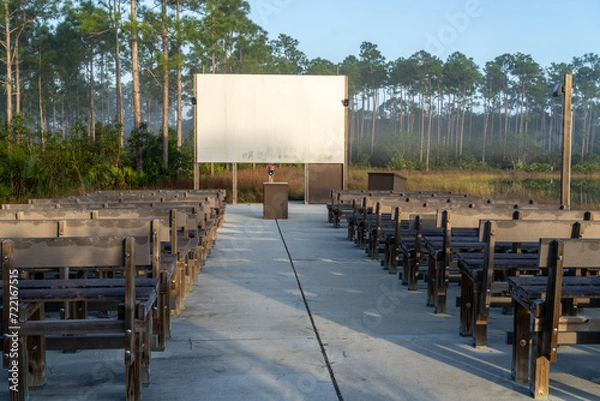 Fototapeta Empty outdoor classroom, lecture, church setting with rows of seating benches, a podium and a white screen board, Long Pine Key Campground, Everglades National Park, Florida