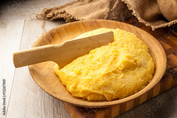 Fototapeta polenta gialla su piatto di legno
