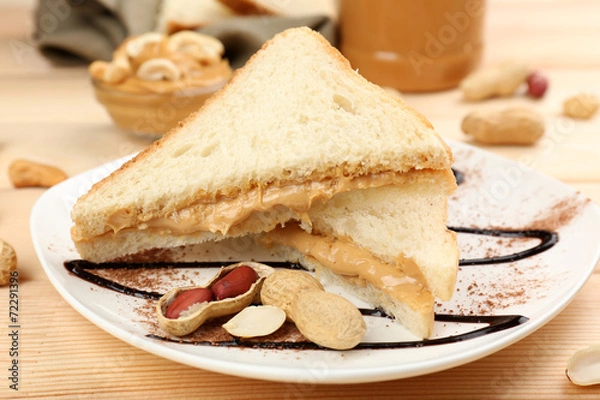 Fototapeta Bread slices with creamy peanut butter on wooden table