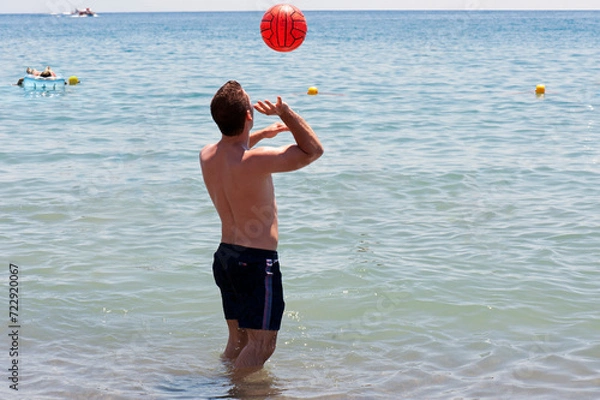 Obraz Young man playing handball in the seashore at the beach.