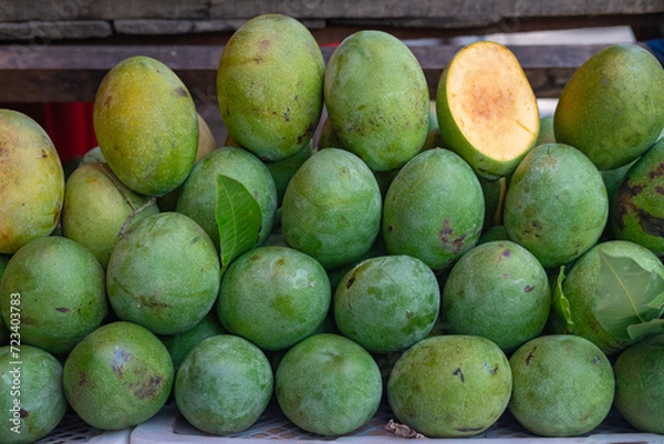 Fototapeta Display of Mangga Manalagi (Manalagi Mango variety) or Honey mango on a market stall. Known for its green skin and yellow with orange spot at the center of its flesh. Very sweet mango.