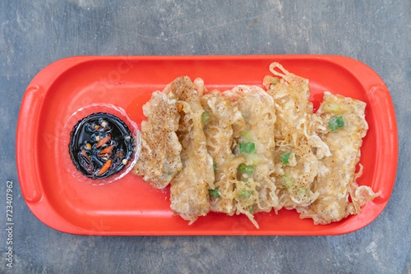 Fototapeta Fried tempeh or tempe goreng, a traditional Indonesian food made from fermented soybean. Served sambal (chili paste) on a red plate. 