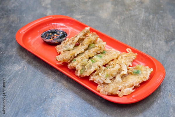 Fototapeta Fried tempeh or tempe goreng, a traditional Indonesian food made from fermented soybean. Served sambal (chili paste) on a red plate. 