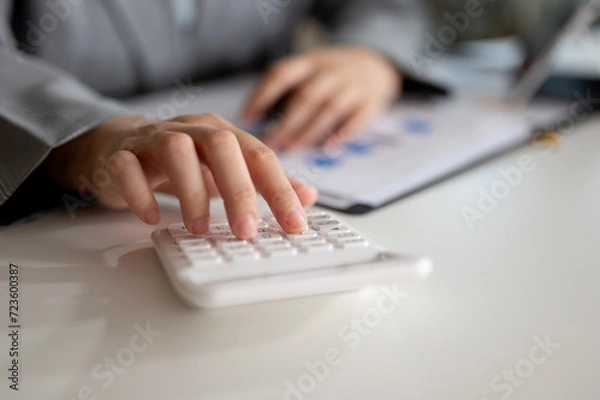 Fototapeta Close-up image of a professional Asian businesswoman using a calculator at a table in her office.
