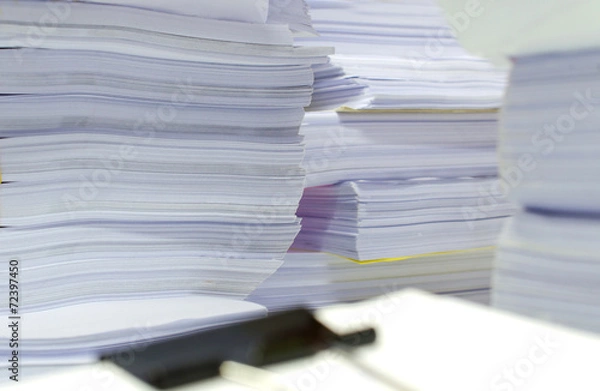 Obraz Pile of documents on desk stack up high waiting to be managed