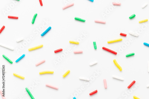 Fototapeta flat lay of colorful sprinkles over white background, festive decoration for banner, poster, flyer, card, postcard, cover, brochure, designers