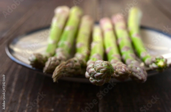 Fototapeta Asparagus on a white plate on the wooden table