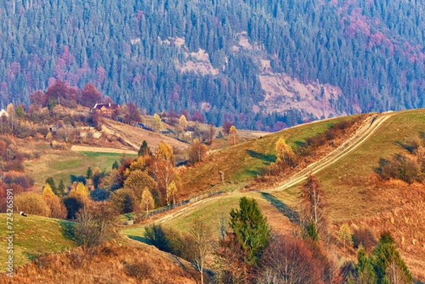 Fototapeta Panoramic view of misty sunny autumn evening in mountains. Beautiful sunset hills landscape. Slopes, meadows, fields, dirt road. Amazing fall rural scene. Tonal perspective Carpathian range.