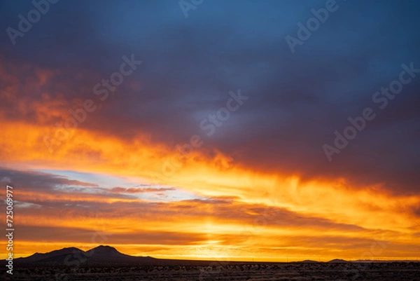 Obraz Mojave desert at sunrise with vivid orange and purple clouds, aerial view, timelapse