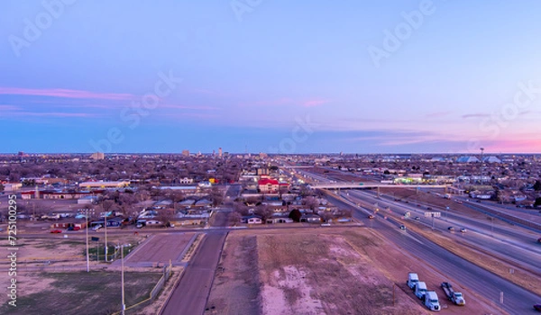 Obraz Aerial Cityscape of Lubbock Texas with traffic on the roads and tall buildings in the background against a blue sky at sunrise.
