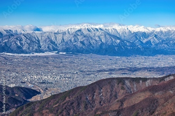 Fototapeta 冠雪の北アルプスの穂高連峰と長野県松本市の街並み