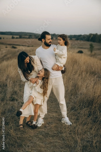 Fototapeta Stylish family in the park in the evening light. Lights of the sun. Mom, dad and child are happy walking at sunset. The concept of a happy family. noise effect