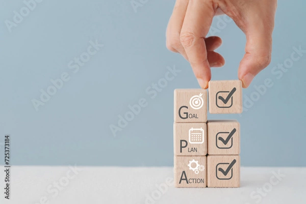 Fototapeta Hand arranged Wooden cube block with Goal, Plan, Action text and icon. Business goals for planning new project, annual plan, business target. including copy space