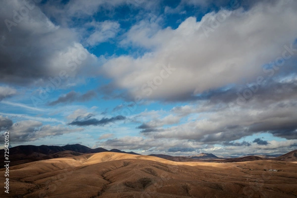 Fototapeta aerial view of a desert landscape on fuerteventura with a cloudy blue sky