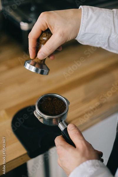 Fototapeta Close-up, the barista works with a temperer. The process of making coffee.