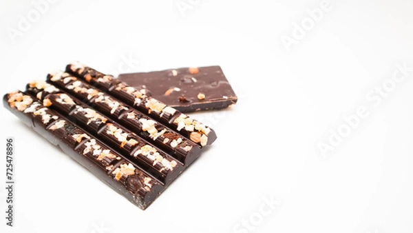 Fototapeta Dark chocolate bars with chopped nuts on a white background, side view. Dessert food. Dark chocolate in Pieces.