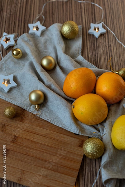 Fototapeta New Year's layout of oranges, board, napkins, garlands and balloons on the kitchen table.Preparations for the holiday.Preparing for the celebration of Christmas.The concept of a cozy kitchen