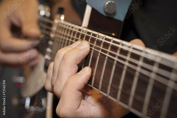 Fototapeta Man with his fingers on the frets of a guitar