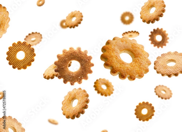 Fototapeta Cookies shaped like flower sprinkled with sugar fly and levitate in space. Volumetric back light. Isolated on white