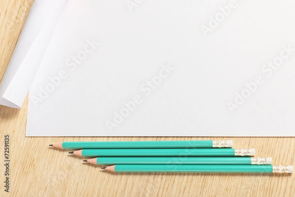 Fototapeta Scroll of paper with  pencils on a wooden surface.