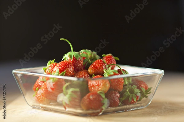 Fototapeta Strawberry fruit in a glass container on a wooden surface with d