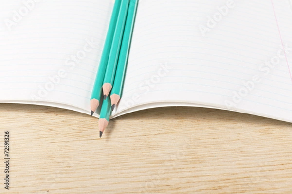 Fototapeta Notebook with pencils and on a wooden surface.