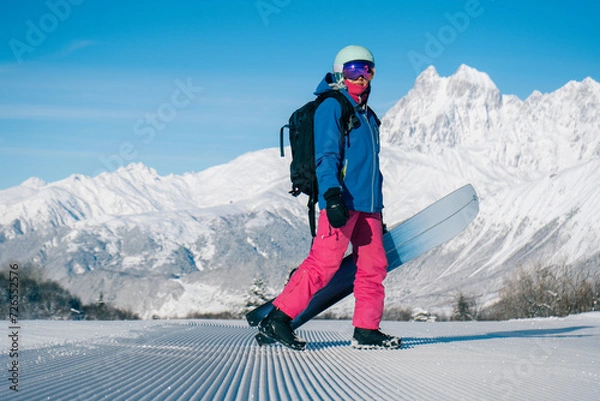 Fototapeta Female snowboarder walking on Snow trail from ratrak preparation, freshly groomed ski slope in high mountains ski resort