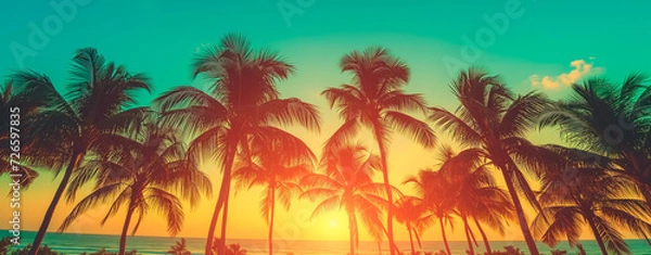 Fototapeta Silhouetted palm trees against a vibrant tropical sunset. Wide banner with copy space.