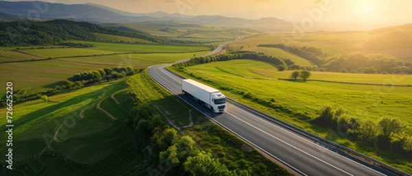 Fototapeta Truck on an open road through vibrant green fields, symbolizing logistics and freedom of travel