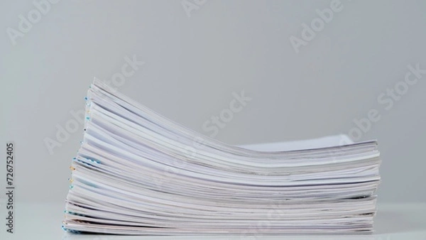 Obraz Time lapse of paper sheets on white background. Stop motion animation of business paper files documents stack with clips at the desk.