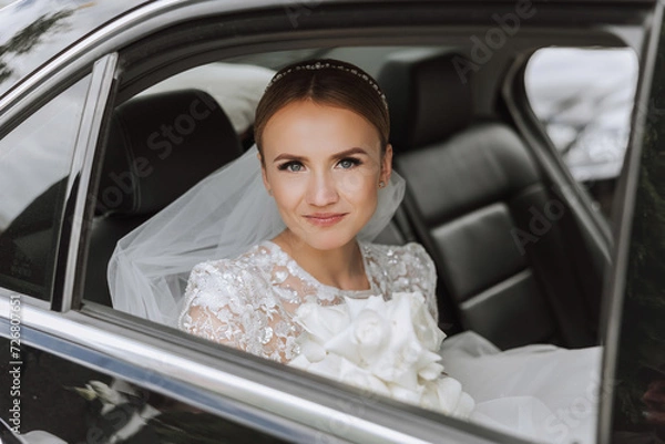 Fototapeta The bride looks out of the car window. Close-up portrait of a pretty shy bride in a car window. Bride smile emotions