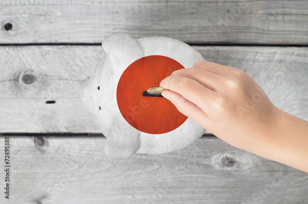Fototapeta Japan saving concept with little hand dropping a coin into piggy