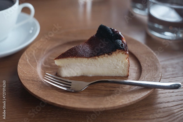 Obraz カフェのテーブル 木のお皿に乗った美味しそうなバスクチーズケーキ